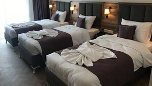 A hotel room with three beds, each with a headboard and bedside lamps. - Royal Palas Hotel (Van)