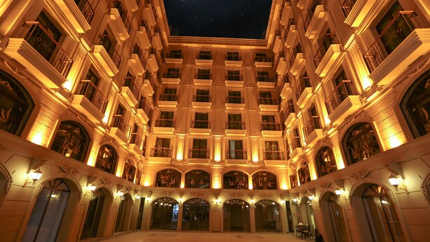 A grand hotel with a central courtyard, multiple balconies, and a view of the moon. - Royal Palas Hotel (Van)