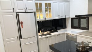 A modern kitchen with white cabinets, a built-in oven, and a black countertop. - Single Eyelid Hostel (Yuanshan)