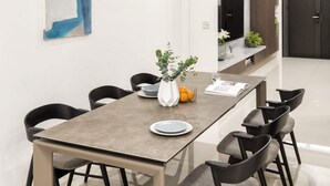 A modern dining area with a long table, six chairs, two pendant lights, a vase with flowers, and a painting on the wall. - Single Eyelid Hostel (Yuanshan)