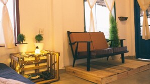 Una habitación acogedora con un banco de madera, una mesita con luces y plantas en macetas.