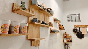 Una cocina con estantes de madera que sostienen utensilios, una ventana y un colgador para ollas.