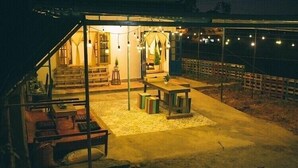 Un espacio al aire libre techado, con un conjunto de asientos y una escalera que lleva a un nivel superior.