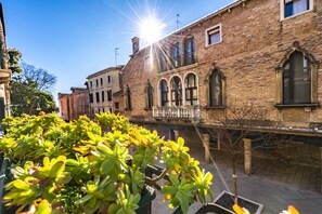 A courtyard with a brick building featuring arched windows and a balcony.