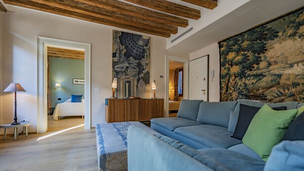 Un salon moderne avec un grand canapé bleu, un plafond en bois et une grande tapisserie au mur.