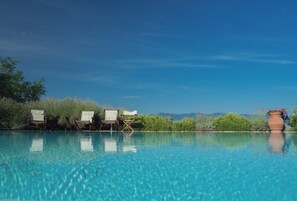 Une piscine d’un bleu éclatant, avec des chaises longues et une plante en pot.