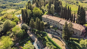 Ein großes Steinhaus, umgeben von üppiger Vegetation und einem Pool.