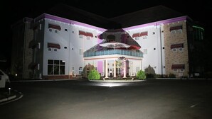 A multi-story hotel with a central atrium, large windows, and a covered entrance area. - Oxygen Holiday Resort (Owerri)