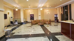 A spacious lobby with a curved sofa, a reception desk, and a marble floor. - Oxygen Holiday Resort (Owerri)
