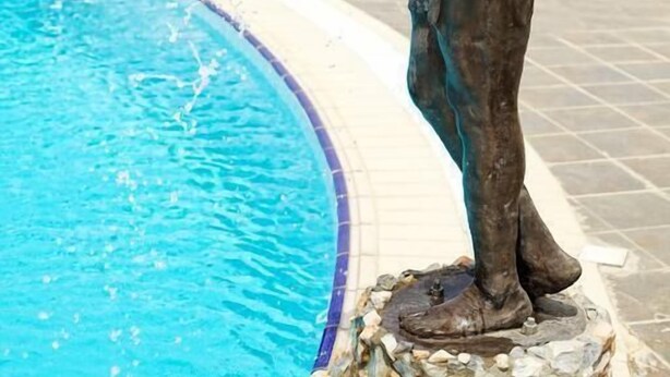 A bronze statue of a child pouring water into a pool. - Oxygen Holiday Resort (Owerri)