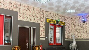 A lobby with a reception desk, a black leather sofa, decorative vases, and a bulletin board advertising a business centre. - Everyday Check Inn Limited (Port Harcourt)