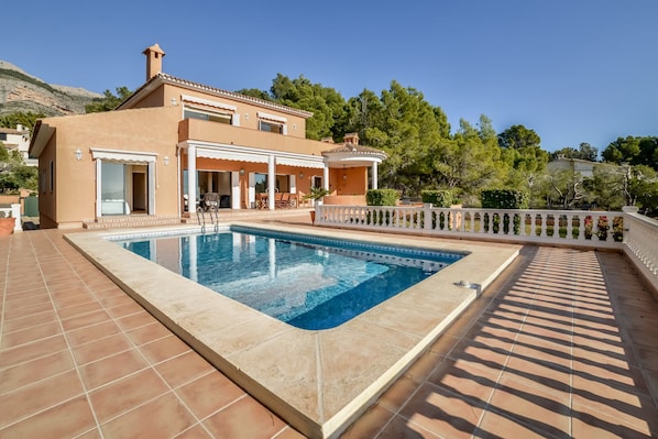 A modern house with a swimming pool, a covered patio, and a view of the surrounding landscape.