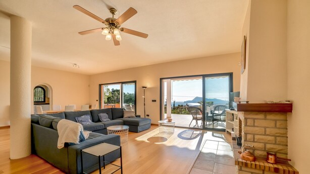 A spacious living room with a large sofa, a coffee table, and a fireplace. There is a balcony with a view of the mountains. - Beautiful villa with private pool and sea views in Altea, Ref 3030 Elena Hills (Altea)