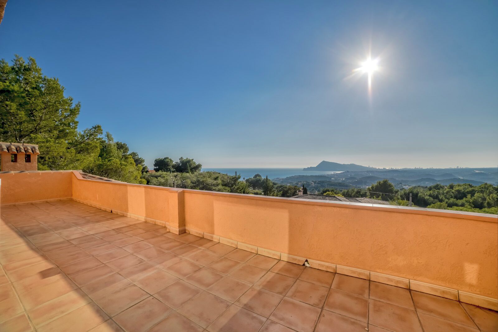 Une terrasse offrant une vue dégagée sur la mer et les montagnes lointaines.