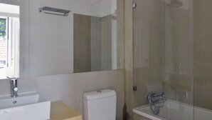 Ein modernes Badezimmer mit einem großen Spiegel, einer Toilette und einer Duschkabine.