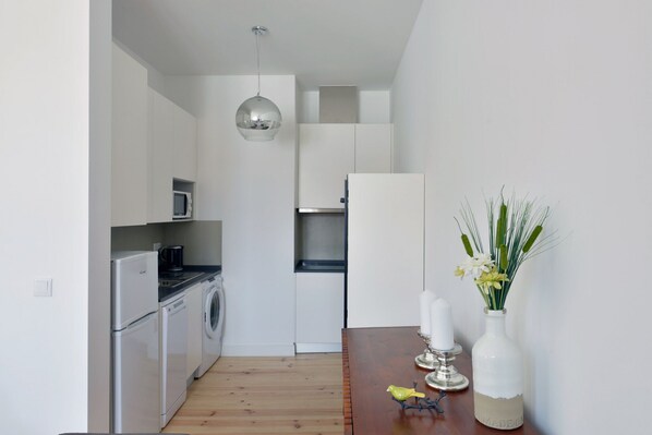 A modern kitchen with stainless steel appliances, a wooden dining table, and a vase with flowers.