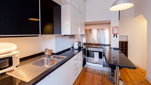 Een moderne keuken met roestvrijstalen apparatuur, een zwart aanrecht en witte kastjes.