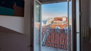 Uitzicht vanaf een balkon met rode dakpannen en een heldere lucht.