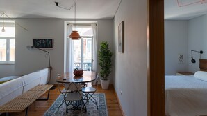 A compact living space with a dining area, a bench, a potted plant, and a bed.