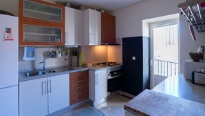 A kitchen with white cabinets, a gas stove, a sink, and a window.