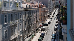A narrow street lined with multi-story buildings, featuring balconies and a mix of residential and commercial spaces.