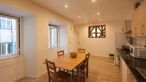 A modern kitchen with wooden cabinets, a dining table with chairs, and a large window providing natural light.