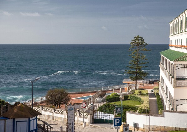 A coastal view with a building, a parking sign, and a street lamp.
