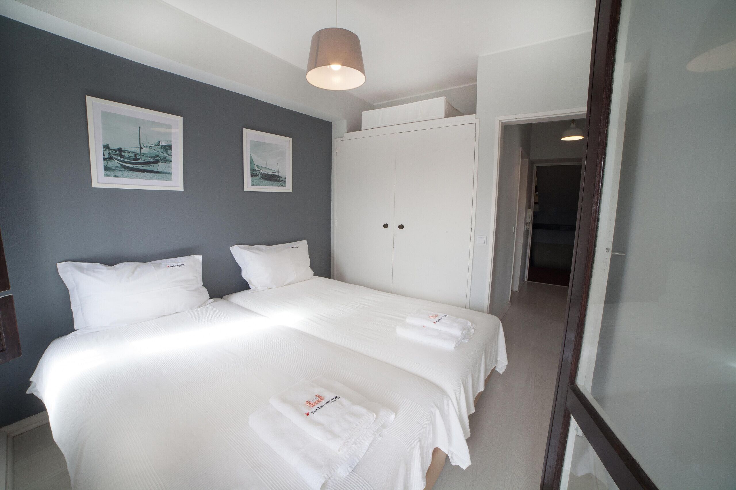Habitación de hotel con dos camas, un armario y un cuadro en la pared.