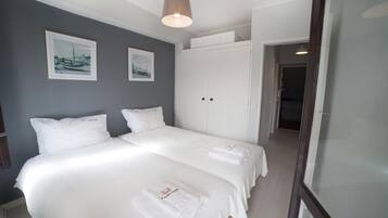 Habitación de hotel con dos camas, un armario y un cuadro en la pared.
