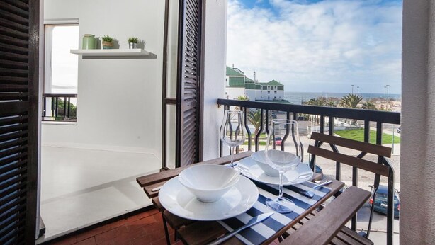 Un balcón con una mesa para dos, con vista al mar.