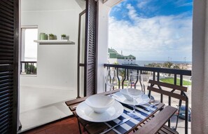Ein Balkon mit Tisch für zwei Personen, mit Blick auf die Küste.