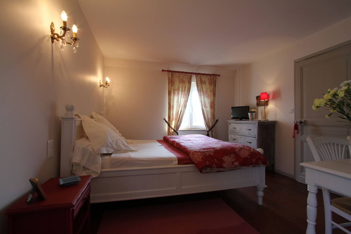 Un dormitorio con una cama individual, mesitas de noche, un escritorio y una silla.