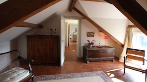 An attic room with exposed wooden beams, a bench, a dresser, and a chair. - Le Clos Xavianne (Ribécourt-la-Tour)