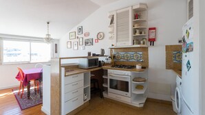 A compact kitchen with a microwave, stove, oven, and a washing machine. There is a dining area with a table and chairs.