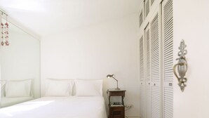 A bedroom with a bed, a nightstand, a lamp, a mirror, and a wardrobe.