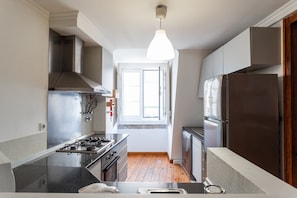 Enjoy cooking in this well-lit kitchen with a gas stove, stainless steel range hood, and large refrigerator.