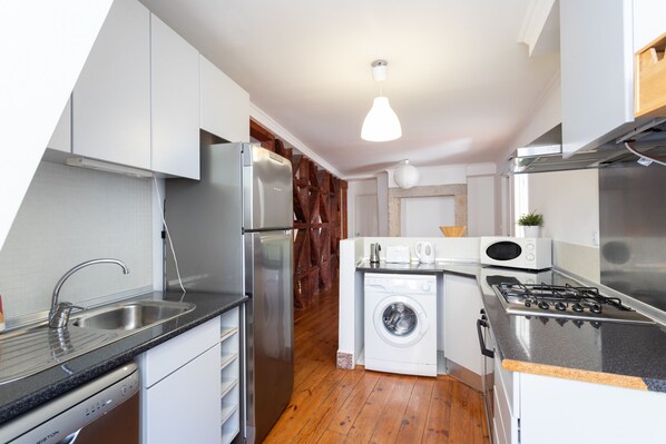 Efficient kitchen with stainless steel appliances, cabinets, and a sink.