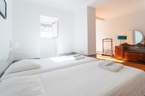 Two single beds with crisp linens and pillows, a dresser, and a mirror.