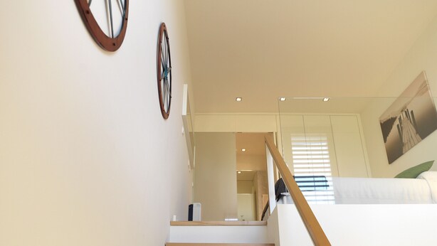 Una escalera con escalones de madera que conduce a un dormitorio en loft con literas.