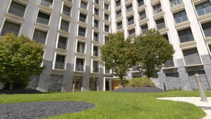 Un edificio moderno de varios pisos con fachada simétrica, ventanas amplias y una entrada central.