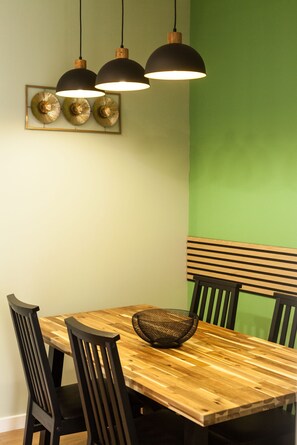 A dining area with a wooden table, black chairs, a woven basket, and three pendant lights.