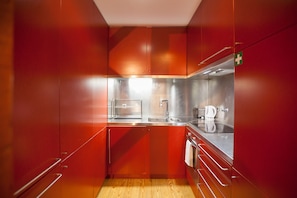 A compact kitchen with stainless steel appliances, a sink, and a coffee maker.