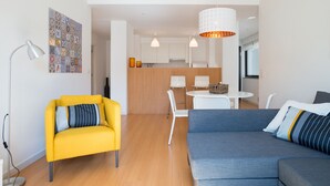 A modern living room with a yellow armchair, a blue sofa, and a dining area with a white table and chairs. - FLH Martim Moniz Castle View Flat (Lisbon)