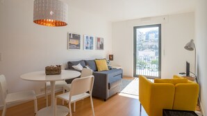 A modern living room with a sofa, a dining table, and a yellow armchair. - FLH Martim Moniz Castle View Flat (Lisbon)