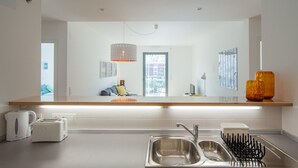 A modern kitchen with a central island, stainless steel sink, and a hanging pendant light. - FLH Martim Moniz Castle View Flat (Lisbon)