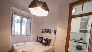 Ein Schlafzimmer mit zwei Betten, einer Waschmaschine und einem Fenster mit Jalousien.
