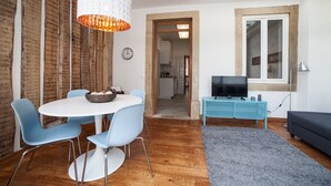 Ein modernes Wohnzimmer mit Essbereich, Fernseher und großem Fenster.
