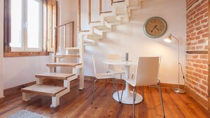 A staircase with wooden steps and white railings, a round table with chairs, and a clock on the wall. - FLH Lisbon Sun Terrace Graça IV (Lisbon)