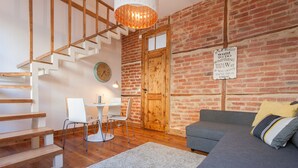 A modern living room with a staircase, a wooden door, and a motivational sign on the wall. - FLH Lisbon Sun Terrace Graça IV (Lisbon)