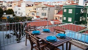 A balcony with a table set for two, overlooking a residential area with red-tiled roofs. - FLH Lisbon Sun Terrace Graça IV (Lisbon)